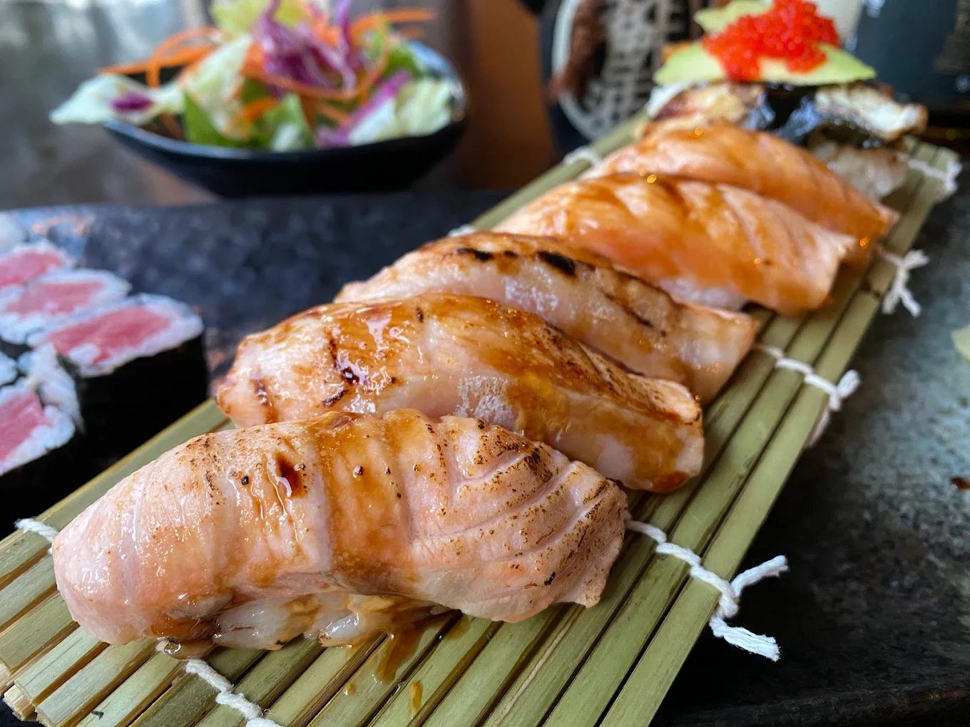Flame-seared salmon nigiri on a bamboo platter